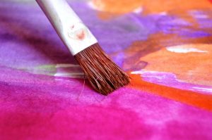 Kreativität entfesseln - wie geht das? Nahaufnahme Pinsel gleitet über Papier mit Farben