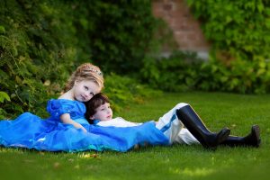 ein Mädchen und ein Junge sitzen im Gras aneinander angeschmiegt , sehr ruhige atmospähre