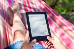 Frau liest Ebook-Reader in Hängematte
