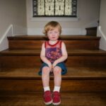 Existenztrauma und Bindungstrauma: Folgen und Heilung Weinendes Mädchen sitzt allein auf einer Treppe – Symbolbild für Existenztrauma und Bindungstrauma in der Kindheit