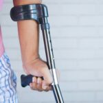 man sieht den ausschnitt von einem Arm mit krücke und rosa t-shirt